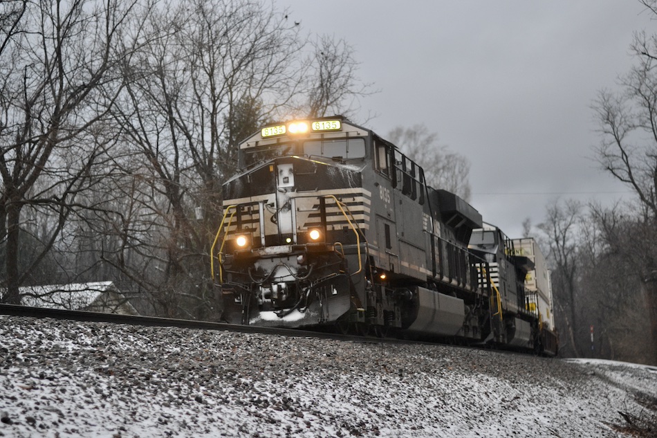 A Norfolk Southern train heads through a bit of snow, sleet, and freezing rain during a gray December day in Virginia.